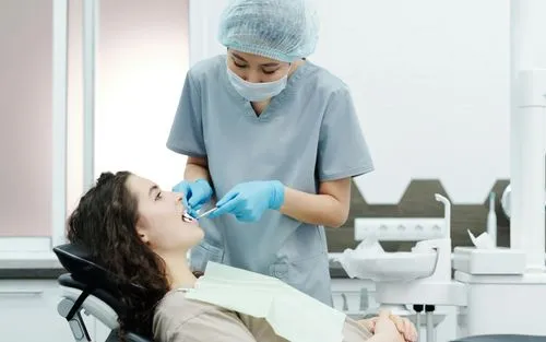 A dentist cleaning a patient's teeth in a modern dental treatment room.